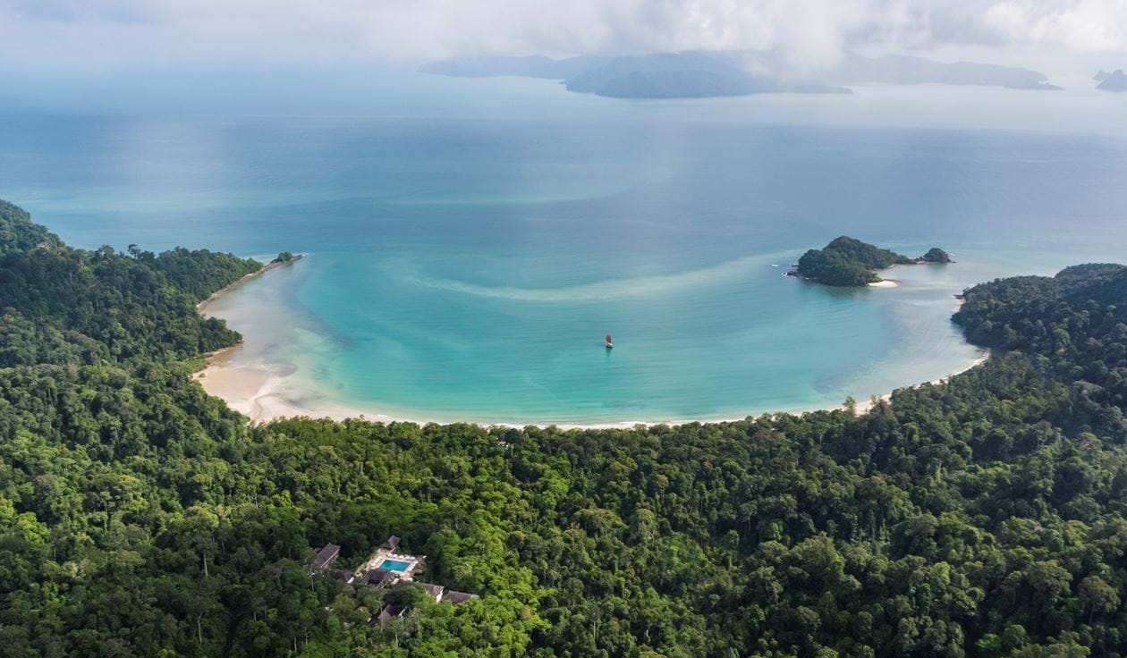 drone shot of the hotel and its rainforest surroundings showing the beach and the water