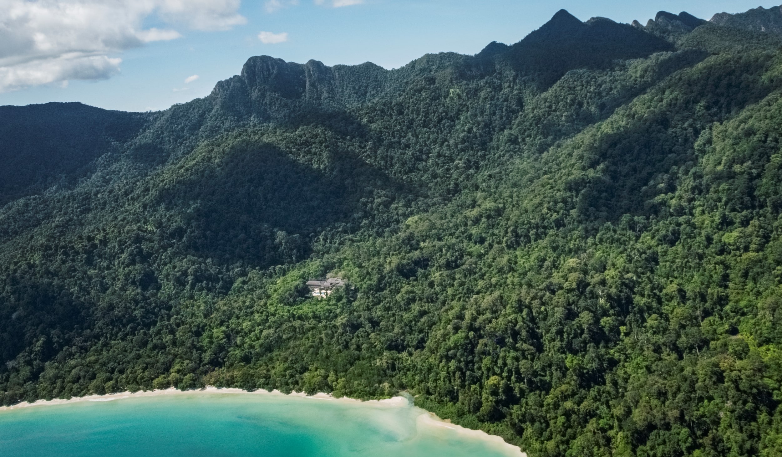 aerial view of the datai and the surrounding rainforest with the beach and and he ocean as well in a sunny setting