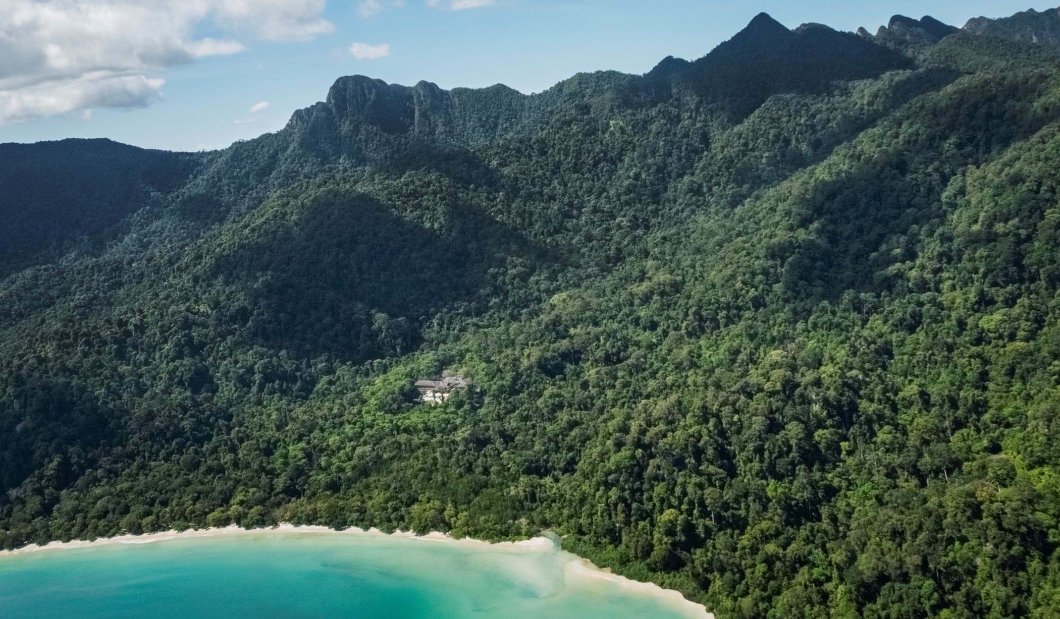 aerial view of the datai and the surrounding rainforest with the beach and and he ocean as well in a sunny setting