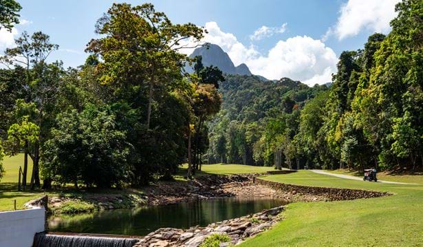 a shot of on e of the holes on the datais els club golf course with a a golf cart  in a sunny setting