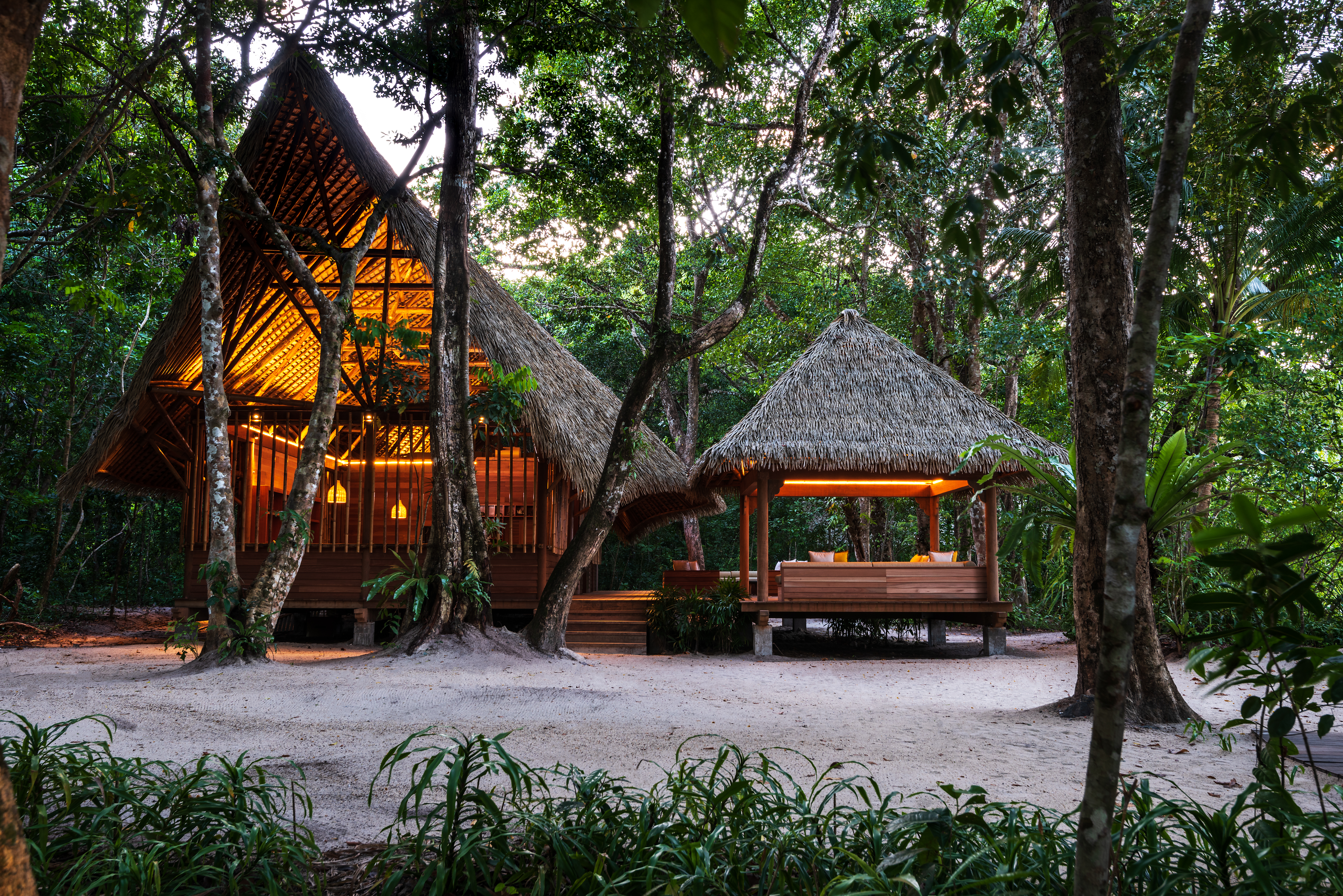 exterior shot of the nature centre in the evening with straw roof and comfy seating area