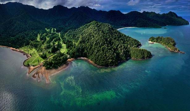 wide exterior shot the the datai els club golf course showcasing the surrounding scenery of the ocean and the rainforest around it