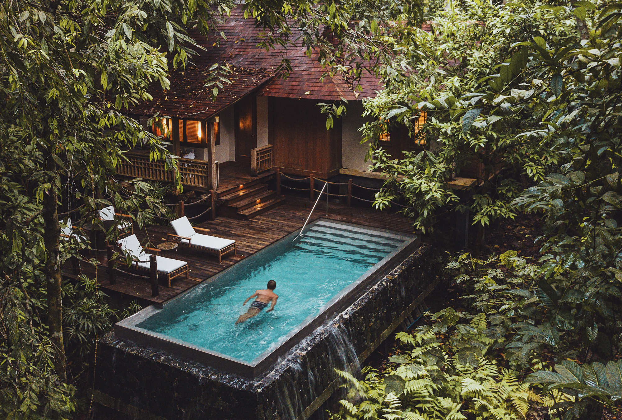 guest swimming through a pool in a rainforest pool villa in cosy sunny setting 