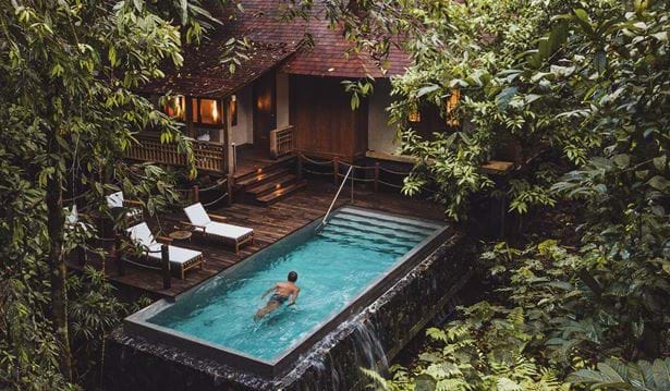 guest swimming through a pool in a rainforest pool villa in cosy sunny setting 