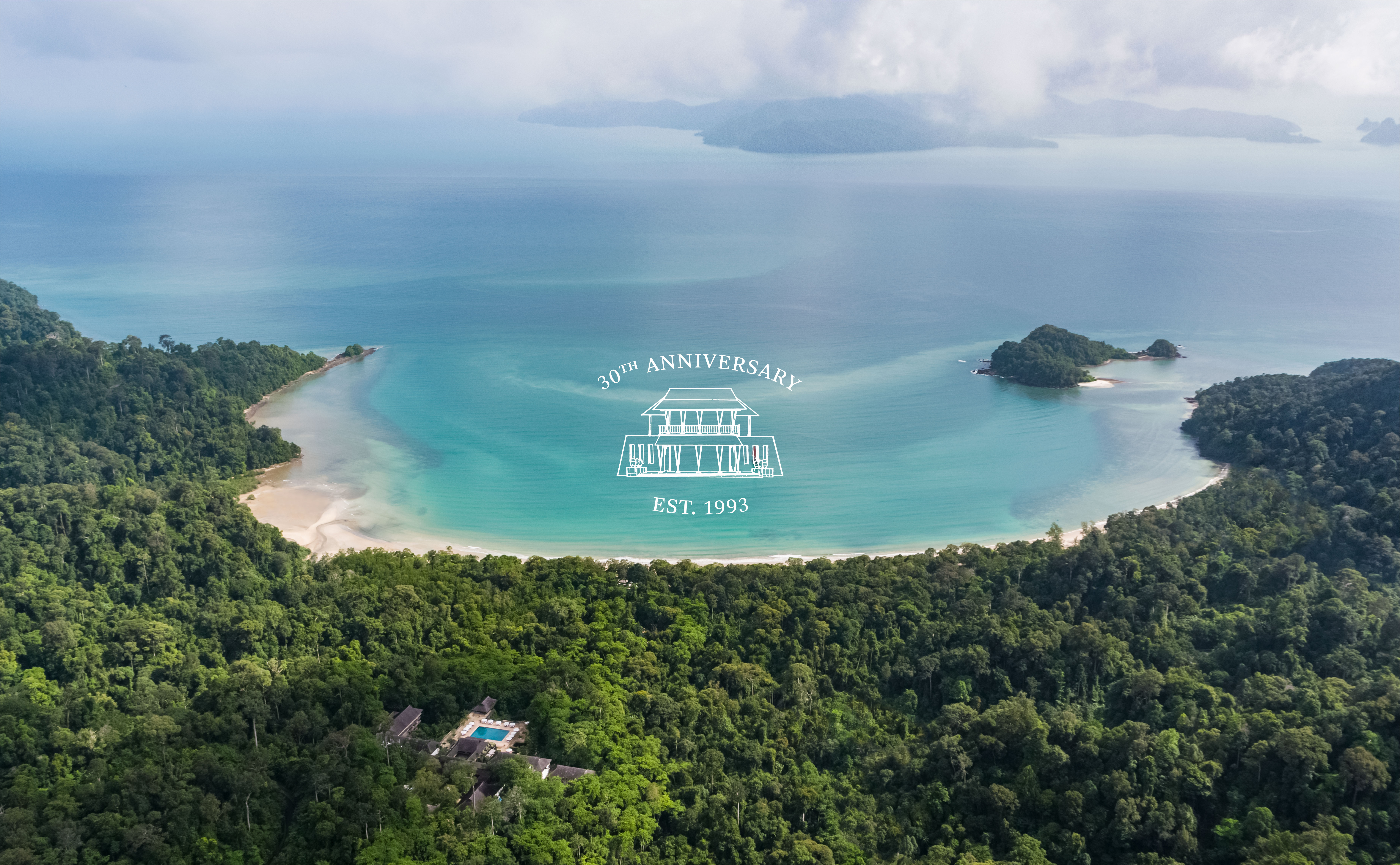 Wide aerial shot of the resort with the datai bay in the background and the 30th anniversary logo in the middle